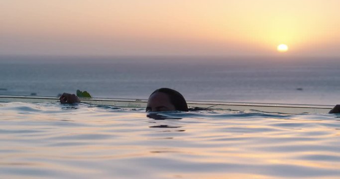 travel woman swimming in pool at luxury hotel spa with beautiful sunset view of ocean mediterranean travel holiday resort relaxing lifestyle freedom 4k