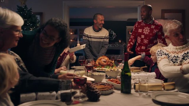 family christmas dinner man cutting turkey serving delicious meal at festive celebration people sitting at table enjoying delicious feast celebrating holiday at home 4k footage