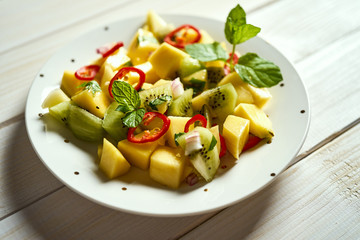 Fresh organic colorful salad with melon on white wooden table