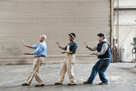 Side view of manager and workers dancing in factory
