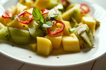 Fresh organic colorful salad with melon on white wooden table