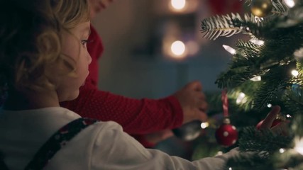 little girls decorating christmas tree with ornaments and baubles enjoying festive celebration at home 4k footage - Powered by Adobe