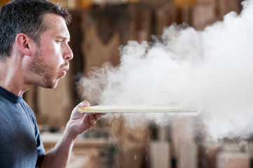 Side view of carpenter blowing sawdust off wooden piece