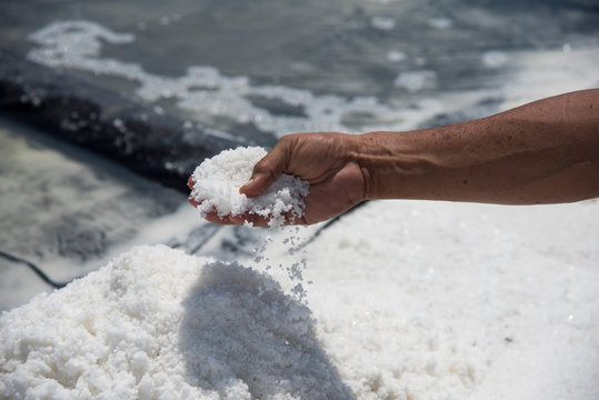 Mano de hombre desmoronando sal de mar pura