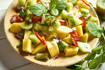 Fresh organic colorful salad with melon on white wooden table