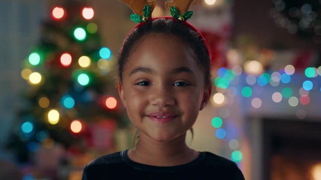 portrait cute african american girl celebrating christmas wearing funny reindeer antlers enjoying festive holiday with colorful lights having fun evening at home 4k footage 