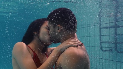 young couple kissing underwater in swimming pool enjoying intimate kiss romantic lovers submerged in water floating with bubbles in passionate intimacy 