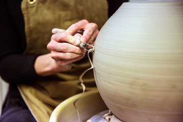 Close up of potter working on clay vase on pottery wheel