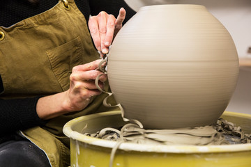 Midsection of potter working on clay vase on pottery wheel