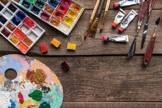 top view of paint palettes and drawing tools on wooden surface with copy space