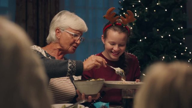 grandmother enjoying christmas dinner with granddaughter eating delicious homemade meal sharing holiday feast with family at home 4k footage
