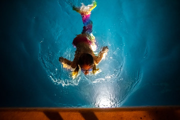 Strange image of a dream in which a girl with colored mermaid tail swims in a lake of calm waters illuminated in a weird way, concept of fantasy and fiction.