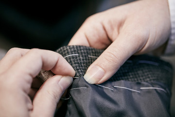 Close up of man's hand sewing with needle and thread