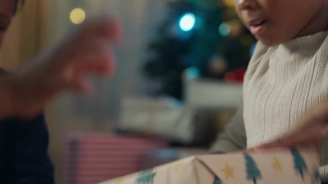 happy african american girl unwrapping christmas presents excited for special gift children having fun enjoying festive holiday celebration with family and friends 4k