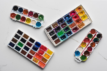 top view of colorful paint palettes on marble white surface