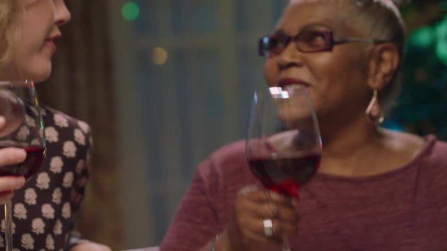 happy old african american woman celebrating christmas dinner with family and friends making toast drinking red wine enjoying festive holiday sitting at table sharing evening meal at home 4k