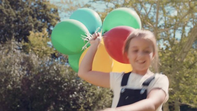 happy little girl running with balloons in park celebrating birthday party having fun summer day feeling excited playfully enjoying childhood freedom outdoors 4k