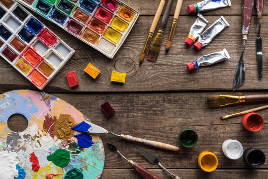 top view of colorful paints and drawing tools on wooden surface with copy space