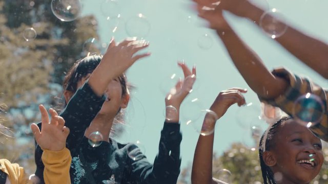 happy little girls playing with soap bubbles blowing in park children having fun summer day friends playing bubble popping game outdoors enjoying childhood freedom 4k
