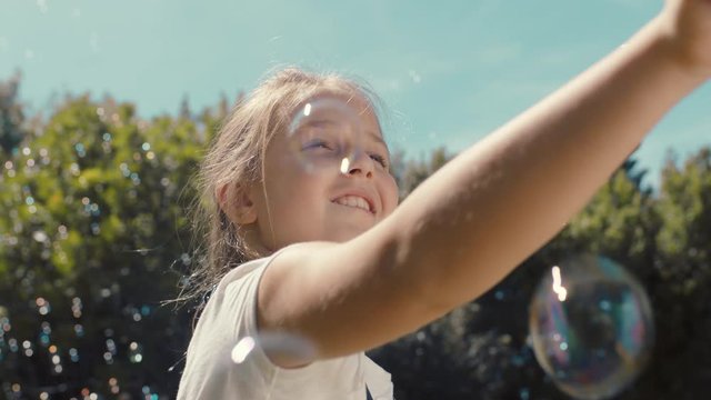 fun little girl catching soap bubbles blowing playfully cute child enjoying summer day playing bubble popping game in park 4k