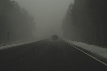 Car moving in snowstorm through the forest. car rides on a winter snowy road in cloudy weather