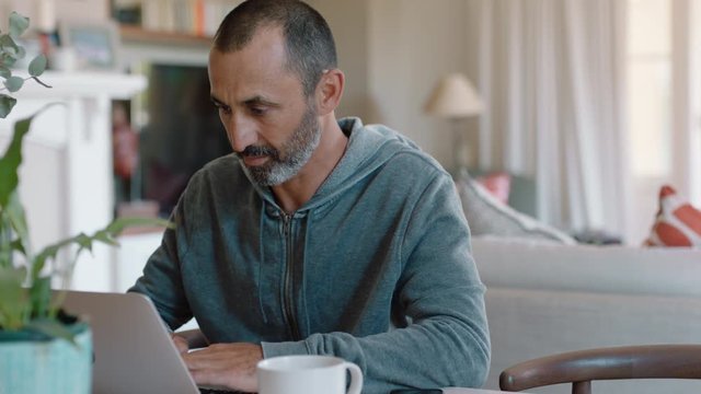 mature man using laptop computer typing emails sending messages drinking coffee enjoying working from home 4k