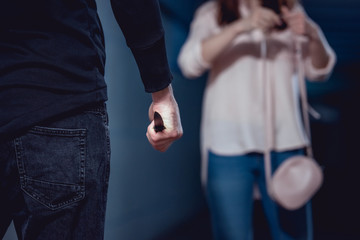 selective focus of thief with knife standing near woman