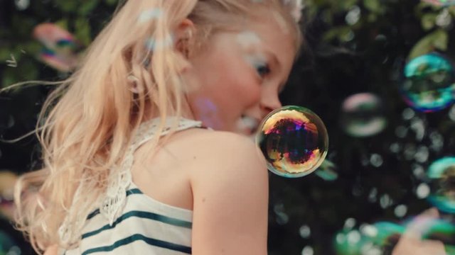 fun little girl catching soap bubbles blowing playfully cute child enjoying summer day playing bubble popping game in park 4k