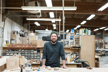 Portrait of smiling carpenter standing in workshop