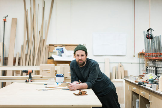 Portrait of carpenter leaning on workbench