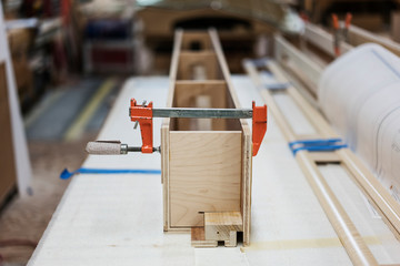 Close up bar clamp on wooden plank in workshop