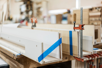 Close up bar clamp on wooden plank in workshop