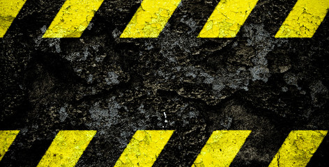 Warning danger sign yellow and black stripes pattern with black area over concrete cement wall...