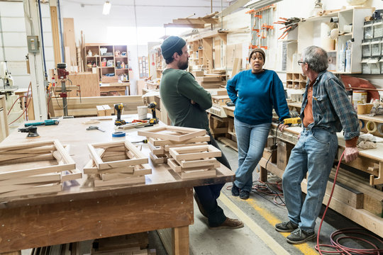 Carpenters talking with each other in workshop