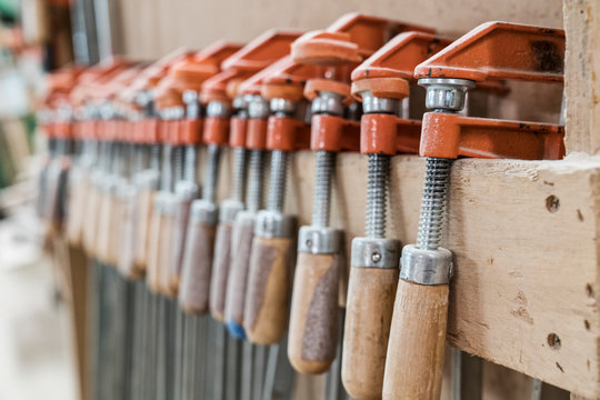 Close up bar clamps on wooden plank in workshop