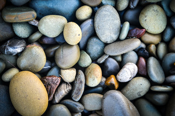 Pebbles on the beach in different colors, cold mood, blues and yellows