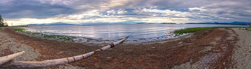 Fototapeta premium Wide Panoramic Scenic Landscape View of Rathtrevor Beach Provincial Park on Vancouver Island and Dramatic Sunset Sky over Strait of Georgia, British Columbia Canada