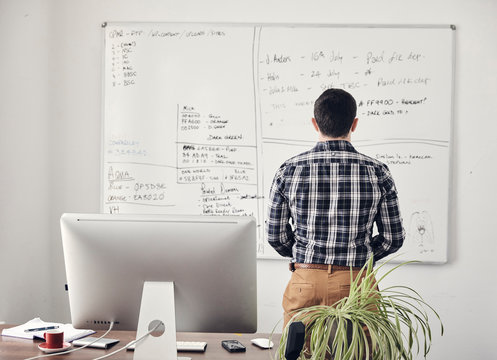 Rear view of businessman looking at whiteboard in office
