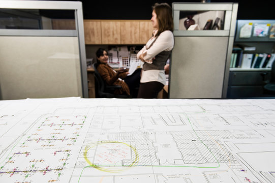 Blueprint on table with businesswomen in background