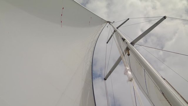 white yacht sails pierce with sky and clouds marine device yachting sailing boat moving on calm waves of the atlantic ocean maritime knot as part of a ship’s outfit Shot on URSA 4.6K (UHD)