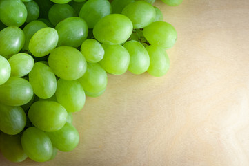 Green grape on top of wooden textural surface. Close-up with copy space