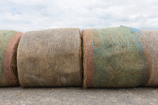 Row of hay bales against cloudy sky