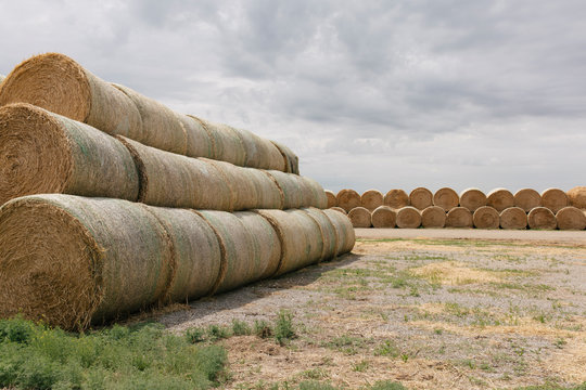 Stack of hay bales in field against cloudy sky