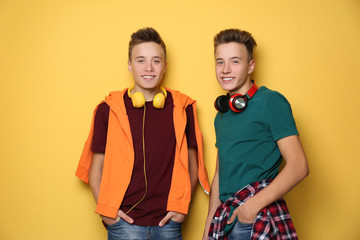 Obraz premium Teenage twin brothers with headphones on color background