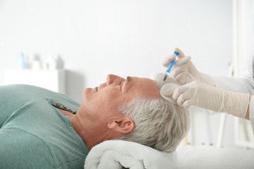 Obraz na płótnie Canvas Senior man with hair loss problem receiving injection in salon