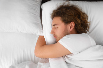 Handsome young man sleeping on pillow, view from above with space for text. Bedtime