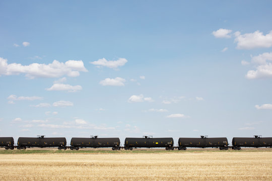 View of oil train cars passing through farmland