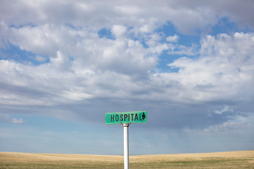 Rural hospital sign against cloudy sky
