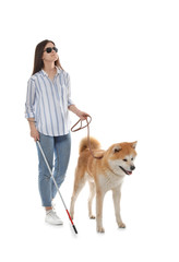 Blind woman with walking stick and dog on leash against white background