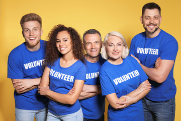 Team of volunteers in uniform on yellow background